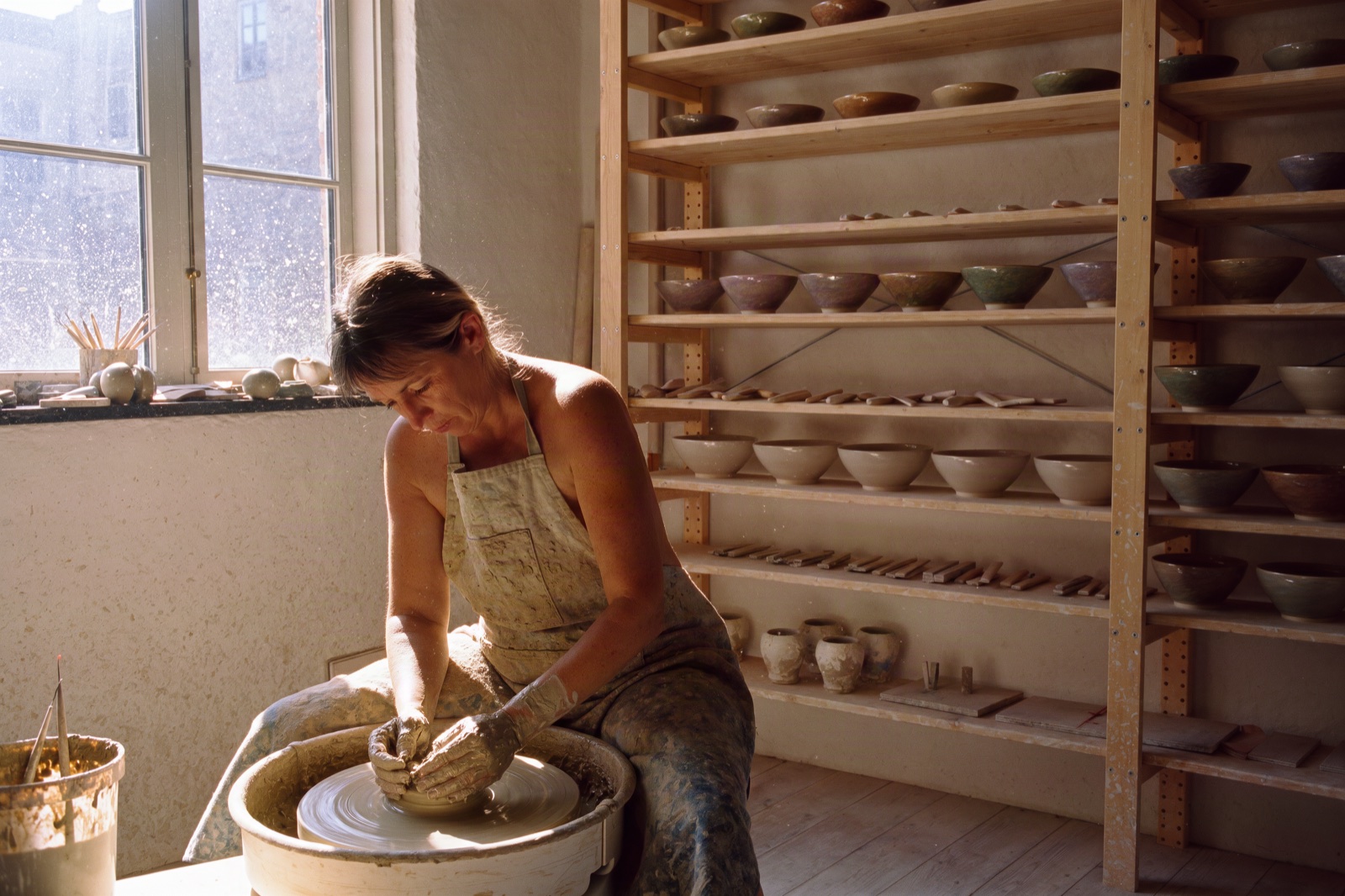 Ceramicist shaping clay at a pottery wheel in a sunlit studio, Krea 3