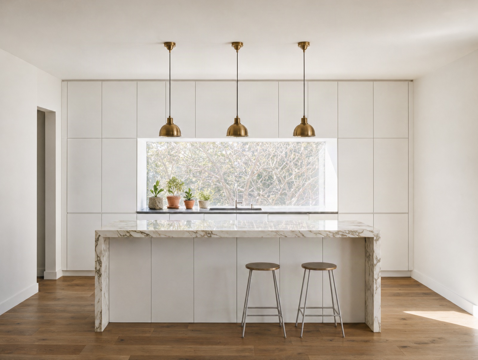 Bright modern white kitchen with a marble island and brass pendants